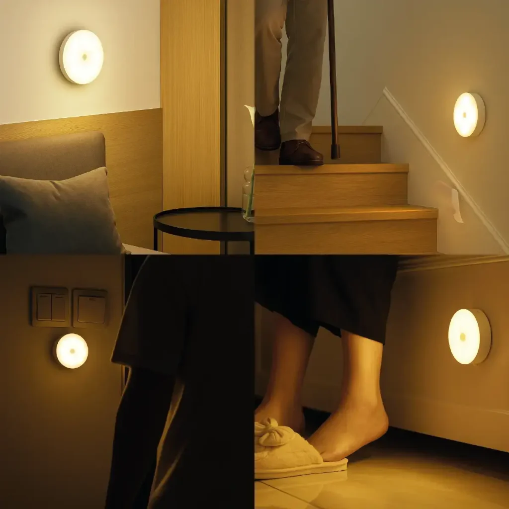 Luminária redonda sem fio presa na parede perto do chão, iluminando de forma suave o rodapé de um corredor escuro.